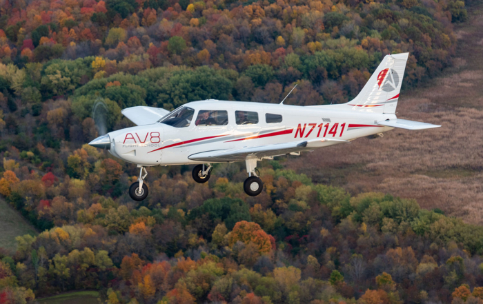piper archer flying over wooded area